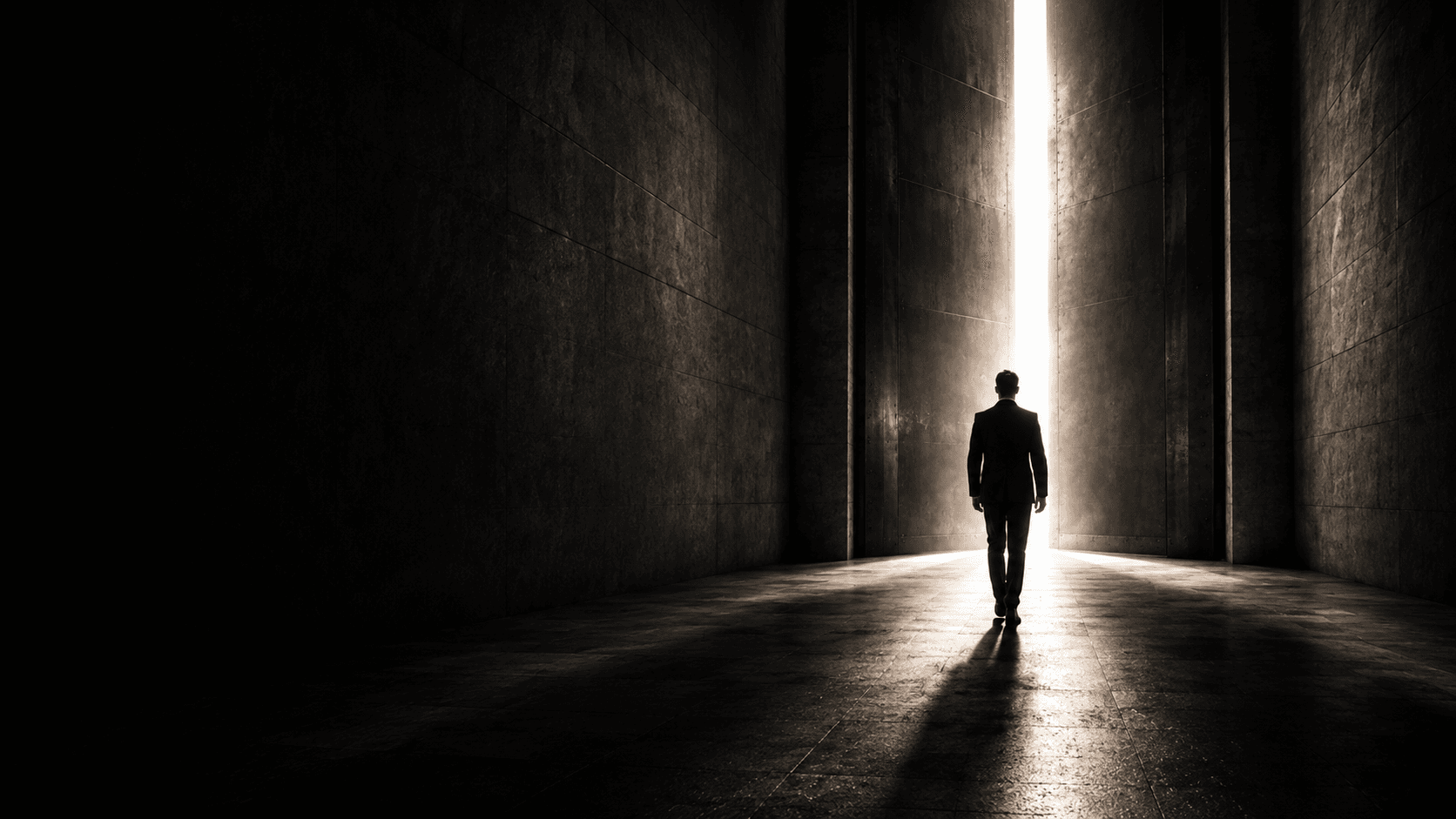 Hombre caminando hacia una abertura de luz en un pasillo de arquitectura oscura